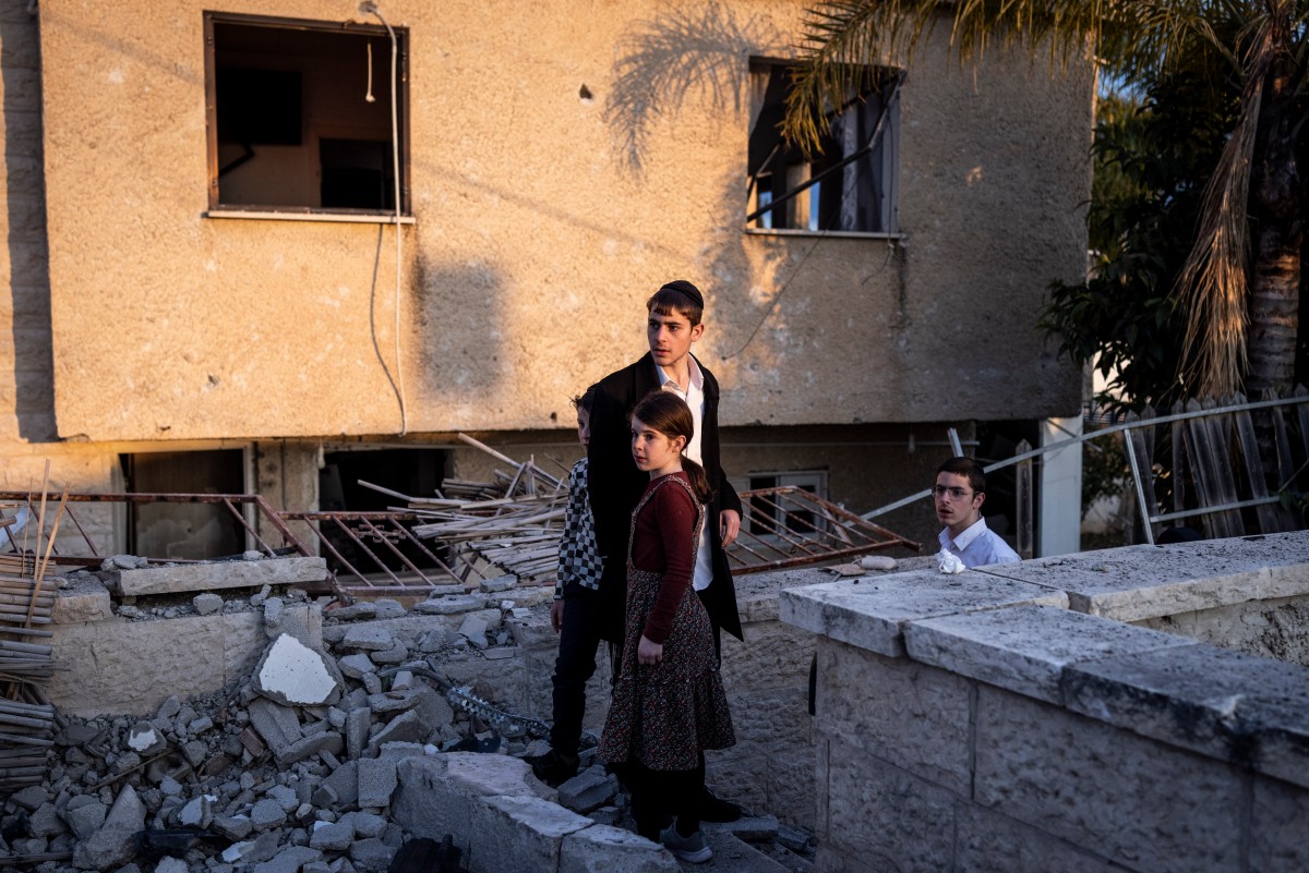 Crianças observam a cena de um ataque de míssil em Bet Shemesh, a cerca de 30 quilômetros a oeste de Jerusalém, em 1º de março de 2026
