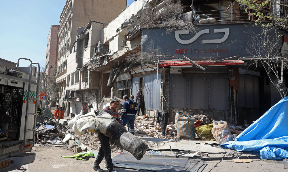 Pessoas inspecionam os destroços de um prédio danificado após ataques aéreos no centro de Teerã, em 4 de março de 2026. A Guarda Revolucionária do Irã afirmou em 4 de março que tinha controle total do Estreito de Ormuz, uma via navegável fundamental para o trânsito global de energia, enquanto Israel lançava uma nova onda de ataques contra a capital iraniana.