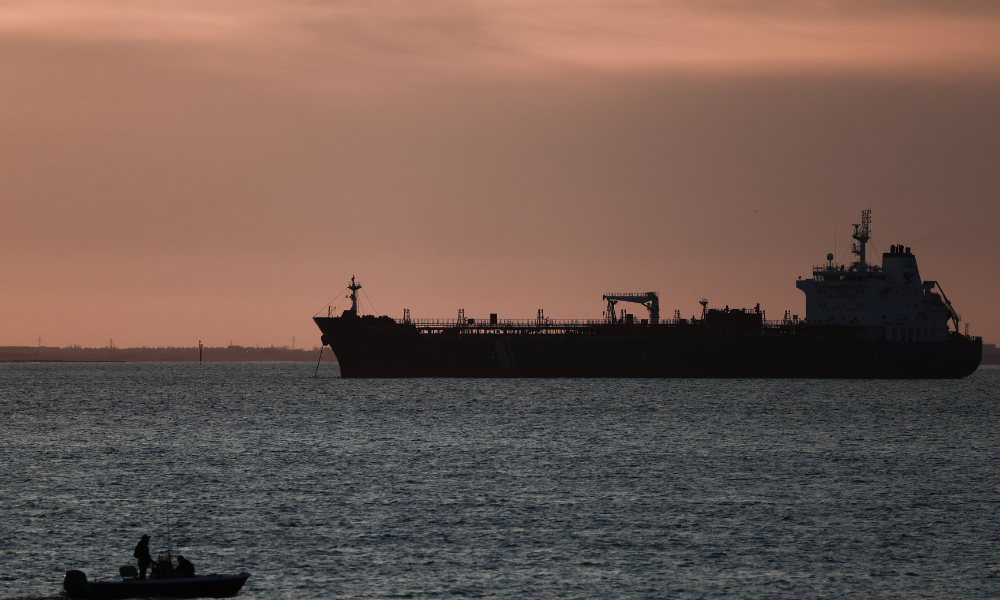 Esta fotografia mostra um pequeno barco em frente a um petroleiro ancorado no Grand Port Maritime de Marseille-Fos, ao pôr do sol, em Fos-sur-Mer, na costa mediterrânica do sul da França, em 13 de março de 2026. (Foto de Thibaud Moritz / AFP)