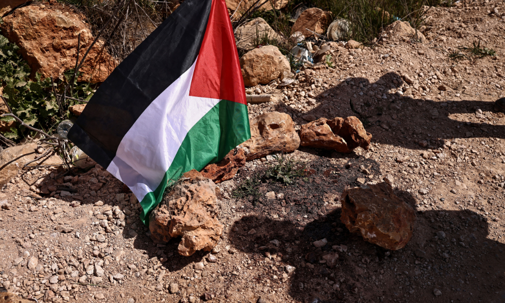 Uma bandeira palestina é colocada no local onde um ataque de colonos judeus matou 3 palestinos e feriu outros 7 em 8 de março, na vila de Abu Falah, a nordeste de Ramallah, na Cisjordânia ocupada por Israel, em 12 de março de 2026. Excluindo Jerusalém Oriental, anexada por Israel, mais de 500.000 israelenses vivem em assentamentos e postos avançados na Cisjordânia, que são ilegais segundo o direito internacional. A violência na Cisjordânia palestina, ocupada por Israel desde 1967, aumentou drasticamente desde que o ataque do Hamas contra Israel desencadeou a guerra em Gaza, em outubro de 2023.