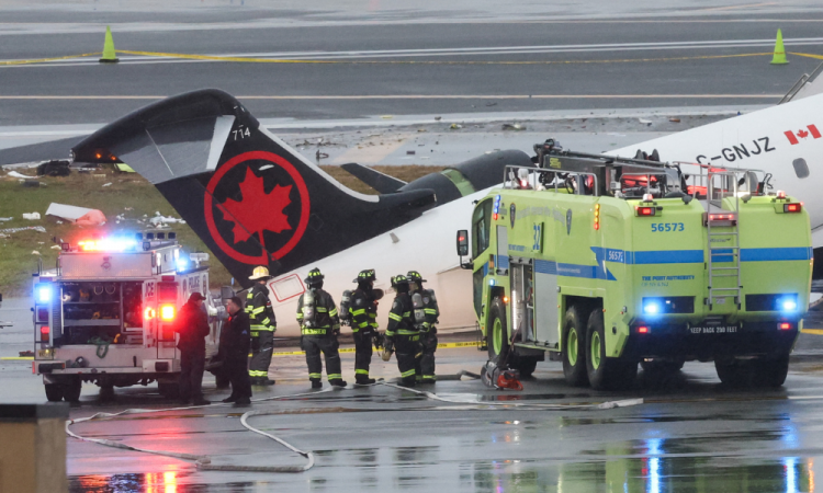 Equipes de emergência trabalham enquanto um CRJ-900 da Air Canada Express permanece na pista após colidir com um caminhão de bombeiros da Autoridade Portuária no Aeroporto LaGuardia, em Nova York, em 23 de março de 2026. Um avião que transportava dezenas de pessoas colidiu com um caminhão de bombeiros em uma pista do aeroporto LaGuardia, em Nova York, matando o piloto e o copiloto e causando "ferimentos graves" em outras pessoas, disseram as autoridades na segunda-feira. Devido ao acidente no final do domingo, as autoridades de aviação dos EUA suspenderam todos os voos em LaGuardia, e a autoridade portuária disse que o aeroporto permaneceria fechado até pelo menos 14h (18h GMT) "para permitir uma investigação completa".