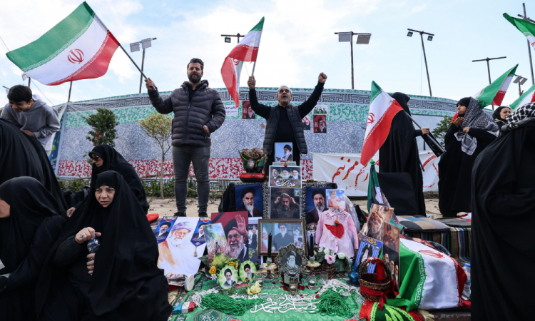 Iranianos acenam com bandeiras nacionais ao lado de um memorial improvisado enquanto se reúnem na Praça da Revolução de Teerã, após os Estados Unidos e o Irã concordarem com um cessar-fogo de duas semanas, em 8 de abril de 2026. Os Estados Unidos e o Irã concordaram com um cessar-fogo de duas semanas pouco antes do prazo de 8 de abril estabelecido pelo presidente dos EUA para obliterar o país, provocando alívio global, bem como apreensão.