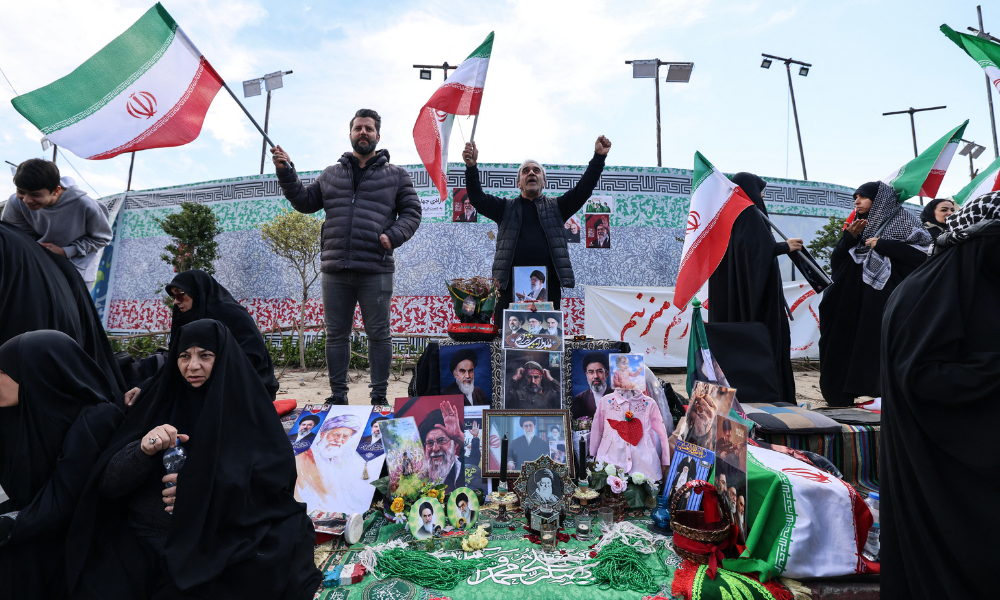 Iranianos acenam com bandeiras nacionais ao lado de um memorial improvisado enquanto se reúnem na Praça da Revolução de Teerã, após os Estados Unidos e o Irã concordarem com um cessar-fogo de duas semanas, em 8 de abril de 2026. Os Estados Unidos e o Irã concordaram com um cessar-fogo de duas semanas pouco antes do prazo de 8 de abril estabelecido pelo presidente dos EUA para obliterar o país, provocando alívio global, bem como apreensão.