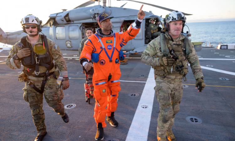 Esta foto divulgada pela NASA mostra o astronauta da NASA Victor Glover, piloto da Artemis II, sendo auxiliado a sair do convés de voo após chegar a bordo do USS John P. Murtha, depois que ele e seus companheiros de tripulação foram resgatados de sua espaçonave Orion após o pouso na água, em 10 de abril de 2026, no Oceano Pacífico, na costa da Califórnia. A espaçonave da NASA que transportou quatro astronautas ao redor da Lua pousou na água conforme planejado na sexta-feira, no Oceano Pacífico. Os membros da tripulação -- Christina Koch, Victor Glover, Jeremy Hansen e Reid Wiseman -- serão recebidos por equipes de resgate e levados para um navio militar dos EUA para avaliações médicas.