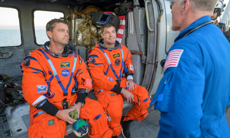 Esta foto divulgada pela NASA mostra o astronauta da NASA Reid Wiseman, comandante da Artemis II (à esquerda), e o astronauta da CSA (Agência Espacial Canadense), Jeremy Hansen, especialista da missão Artemis II, conversando com o médico de voo da NASA, Richard Scheuring, em seu helicóptero MH-60 Seahawk da Esquadrilha de Combate Marítimo de Helicópteros (HSC) 23, no convés de voo do USS John P. Murtha, depois que eles e seus companheiros de tripulação foram resgatados de sua espaçonave Orion após o pouso na água, em 10 de abril de 2026, no Oceano Pacífico, na costa da Califórnia. A espaçonave da NASA que transportou quatro astronautas ao redor da Lua pousou na água conforme planejado na sexta-feira, no Oceano Pacífico. Os membros da tripulação -- Christina Koch, Victor Glover, Jeremy Hansen e Reid Wiseman -- serão recebidos por equipes de resgate e levados para um navio militar dos EUA para avaliações médicas.