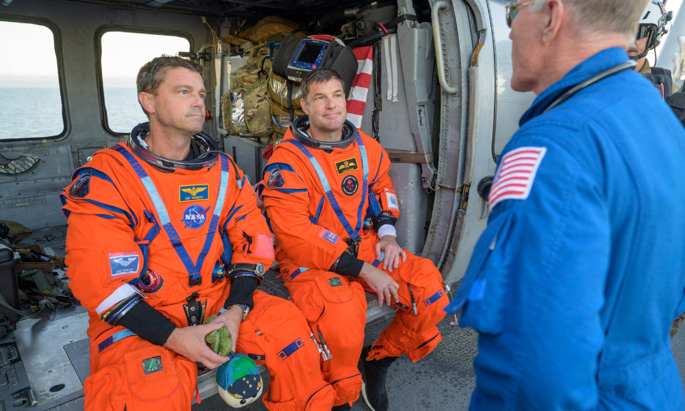 Esta foto divulgada pela NASA mostra o astronauta da NASA Reid Wiseman, comandante da Artemis II (à esquerda), e o astronauta da CSA (Agência Espacial Canadense), Jeremy Hansen, especialista da missão Artemis II, conversando com o médico de voo da NASA, Richard Scheuring, em seu helicóptero MH-60 Seahawk da Esquadrilha de Combate Marítimo de Helicópteros (HSC) 23, no convés de voo do USS John P. Murtha, depois que eles e seus companheiros de tripulação foram resgatados de sua espaçonave Orion após o pouso na água, em 10 de abril de 2026, no Oceano Pacífico, na costa da Califórnia. A espaçonave da NASA que transportou quatro astronautas ao redor da Lua pousou na água conforme planejado na sexta-feira, no Oceano Pacífico. Os membros da tripulação -- Christina Koch, Victor Glover, Jeremy Hansen e Reid Wiseman -- serão recebidos por equipes de resgate e levados para um navio militar dos EUA para avaliações médicas.