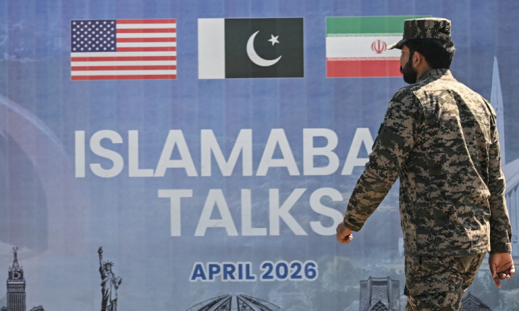 Um guarda florestal paquistanês passa por um cartaz sobre as negociações de paz entre os EUA e o Irã em Islamabad, em 12 de abril de 2026. O Irã e os Estados Unidos não conseguiram chegar a um acordo para encerrar a guerra no Oriente Médio, disse o vice-presidente dos EUA, JD Vance, em 12 de abril, após longas negociações em Islamabad, acrescentando que estava deixando as negociações depois de apresentar a Teerã a "oferta final e melhor". Conteúdo relacionado