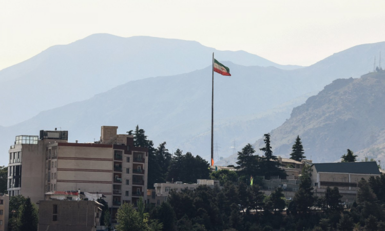 Bandeira do Irã tremula em um mastro alto sobre arranha-céus no norte de Teerã, em 12 de maio de 2026