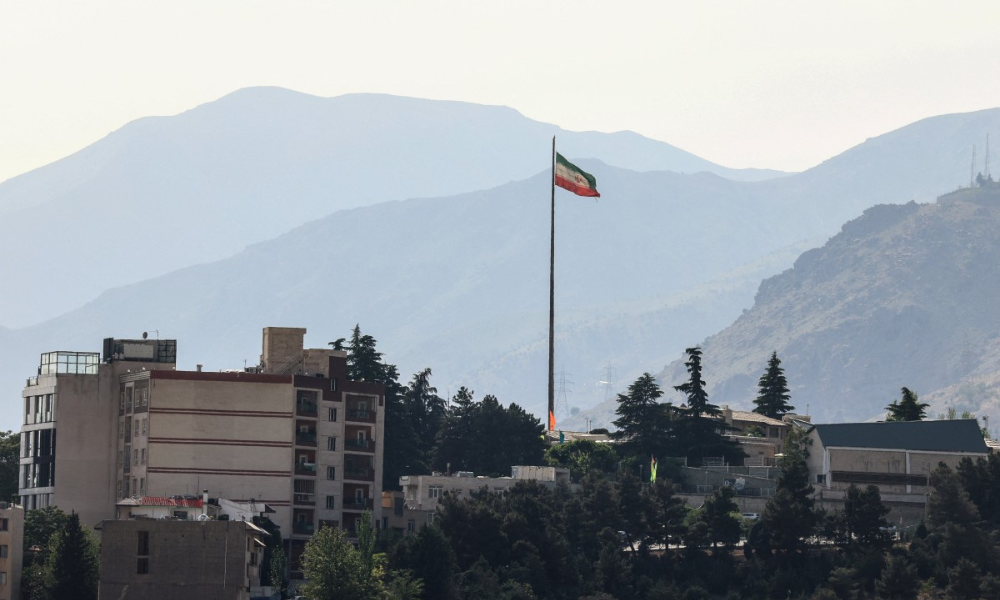 Bandeira do Irã tremula em um mastro alto sobre arranha-céus no norte de Teerã, em 12 de maio de 2026