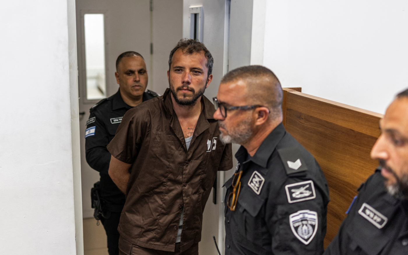 Agentes de segurança escoltam o ativista brasileiro Thiago Ávila até um tribunal em Ashkelon, em 3 de maio de 2026. Dois ativistas estrangeiros de uma flotilha com destino a Gaza, que foram levados a Israel para interrogatório, compareceram perante um tribunal israelense em 3 de maio, informou à AFP um grupo de direitos humanos que os defende. A flotilha, com mais de 50 embarcações, partiu da França, Espanha e Itália com o objetivo de romper o bloqueio israelense a Gaza e levar suprimentos ao território palestino devastado. Conteúdo relacionado