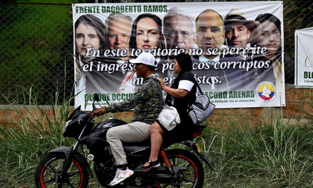 Uma motocicleta passa por uma faixa assinada pela facção de Dagoberto Ramos, dissidentes da guerrilha FARC, que insta as pessoas a votarem contra políticos de direita antes da eleição presidencial em Caloto, departamento de Cauca, Colômbia, em 28 de maio de 2026. A Colômbia realizará uma eleição presidencial em 31 de maio de 2026.