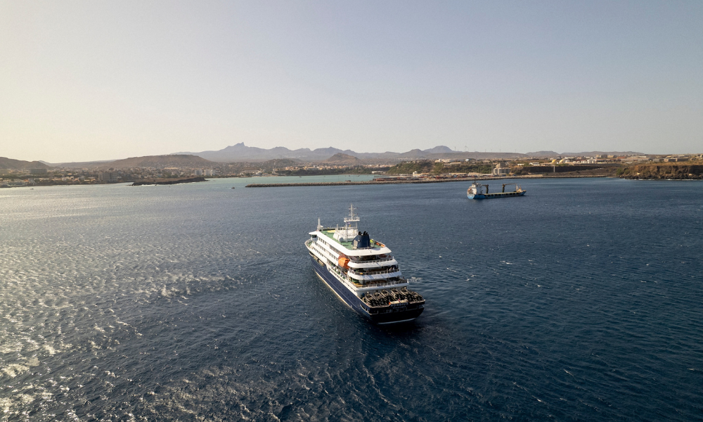Esta imagem aérea mostra uma vista geral do navio de cruzeiro MV Hondius atracado ao largo do porto de Praia, capital de Cabo Verde, em 3 de maio de 2026. Um surto de "doença respiratória aguda grave" a bordo de um navio de cruzeiro no Atlântico deixou duas pessoas mortas e uma terceira em terapia intensiva em Joanesburgo, informou o Ministério da Saúde da África do Sul à AFP em 3 de maio de 2026. O surto ocorreu no MV Hondius, que viajava de Ushuaia, na Argentina, para Cabo Verde. O paciente em tratamento em Joanesburgo testou positivo para hantavírus, uma família de vírus que pode causar febre hemorrágica, disse o porta-voz sul-africano Foster Mohale. Conteúdo relacionado