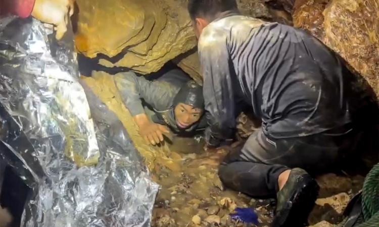 Equipe de resgate libertando um dos sete homens (à esquerda) presos dentro de uma caverna em Laos