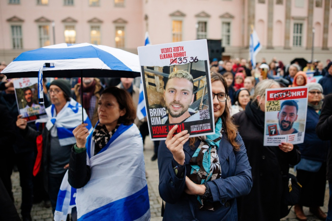 Participantes seguram cartazes com retratos dos reféns durante vigília em memória ao segundo aniversário do ataque do Hamas contra Israel na praça Bebelplatz